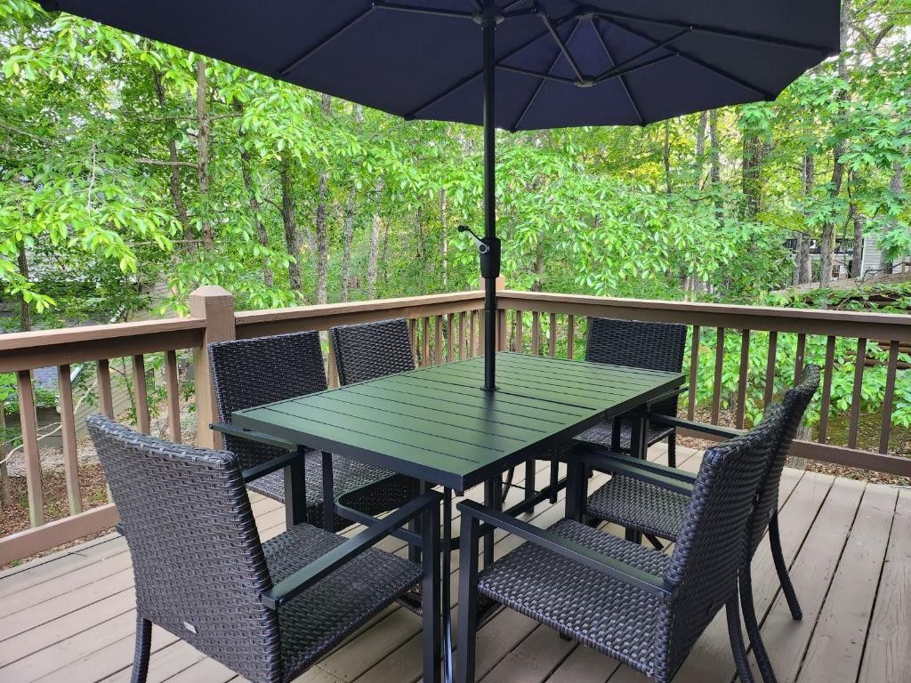 Outdoor dining table beneath an umbrella surrounded by green trees